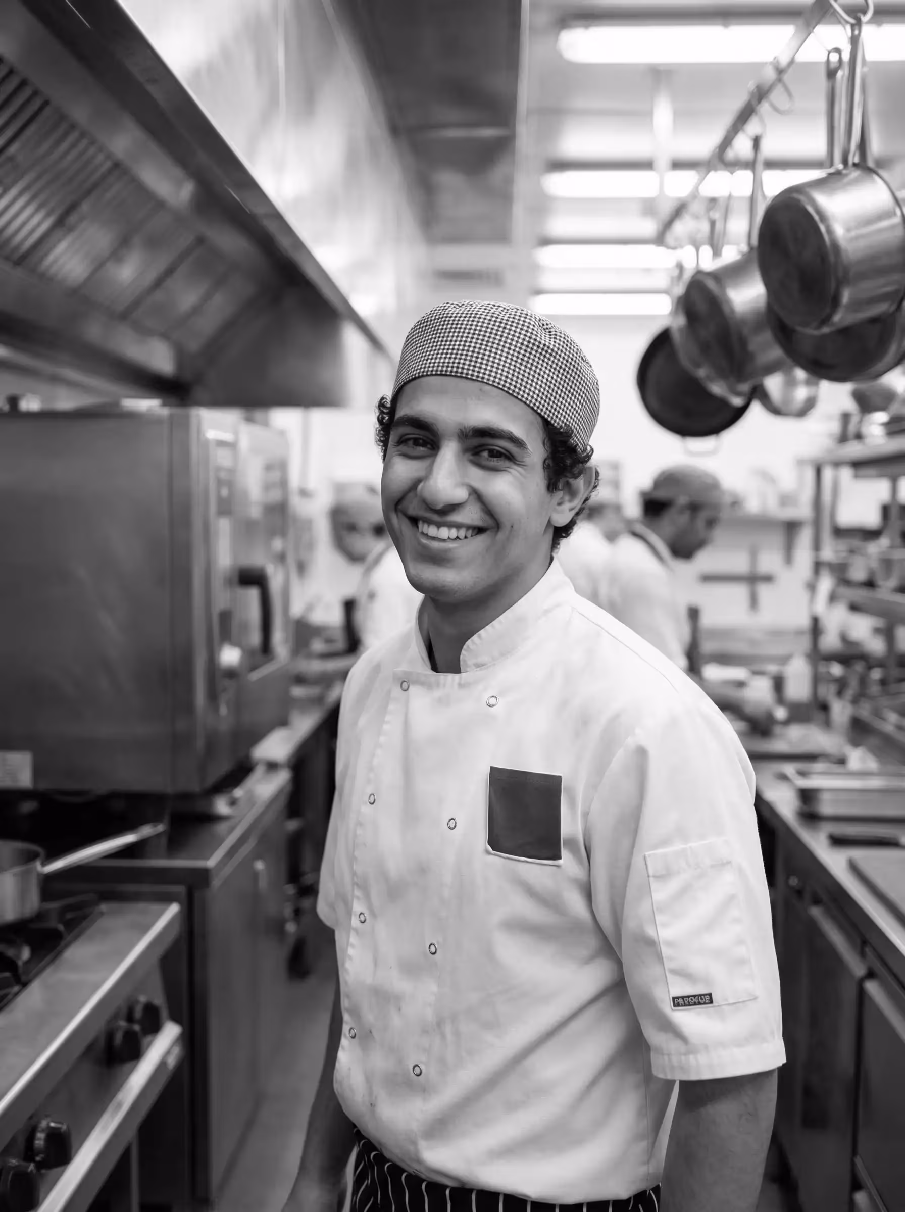 ritratto in studio di uno chef con grembiule verde scuro, illuminazione laterale drammatica e sfondo intenso