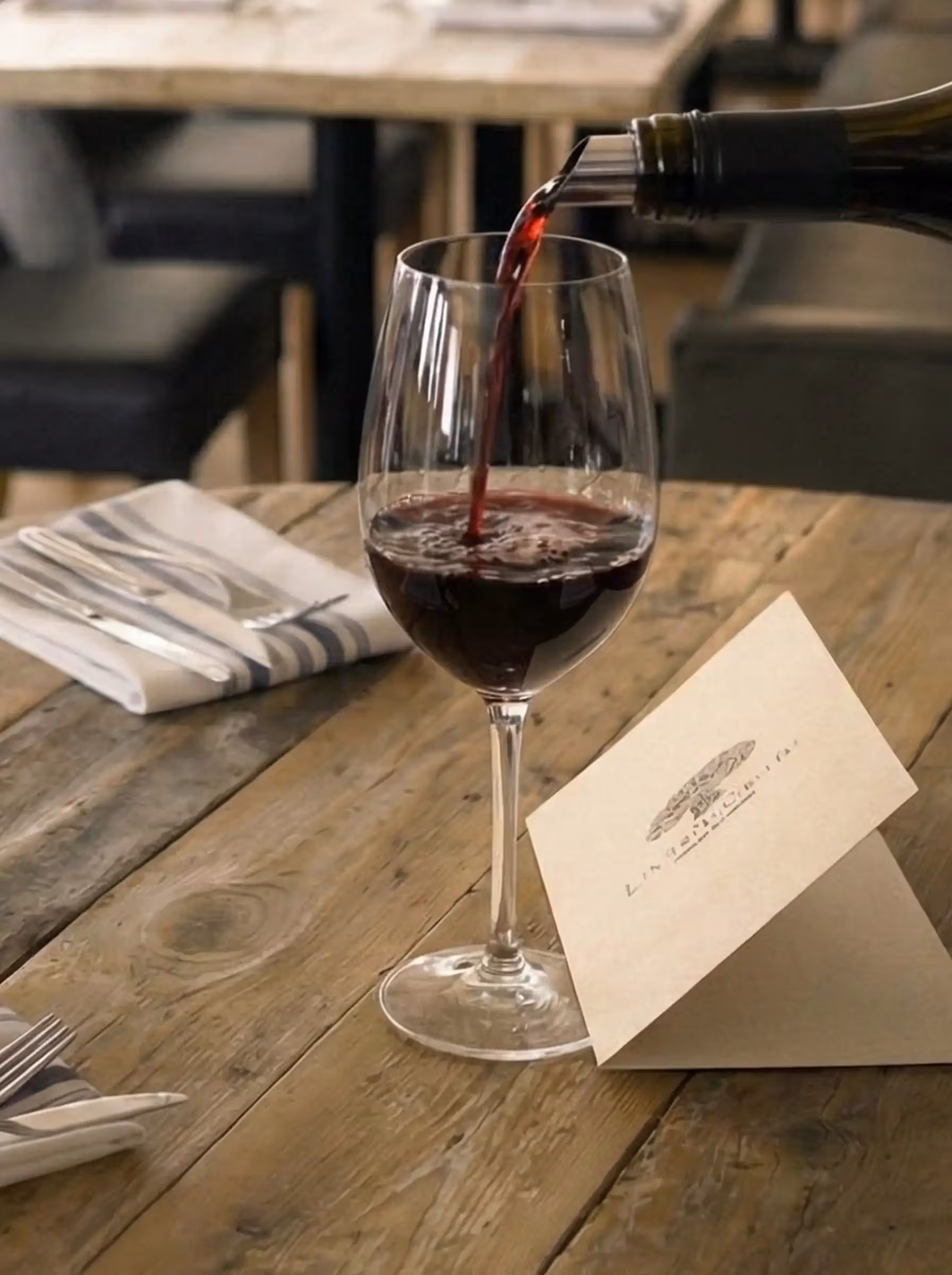 detail shot of a crystal glass being filled with aged red wine in a dimly lit cellar