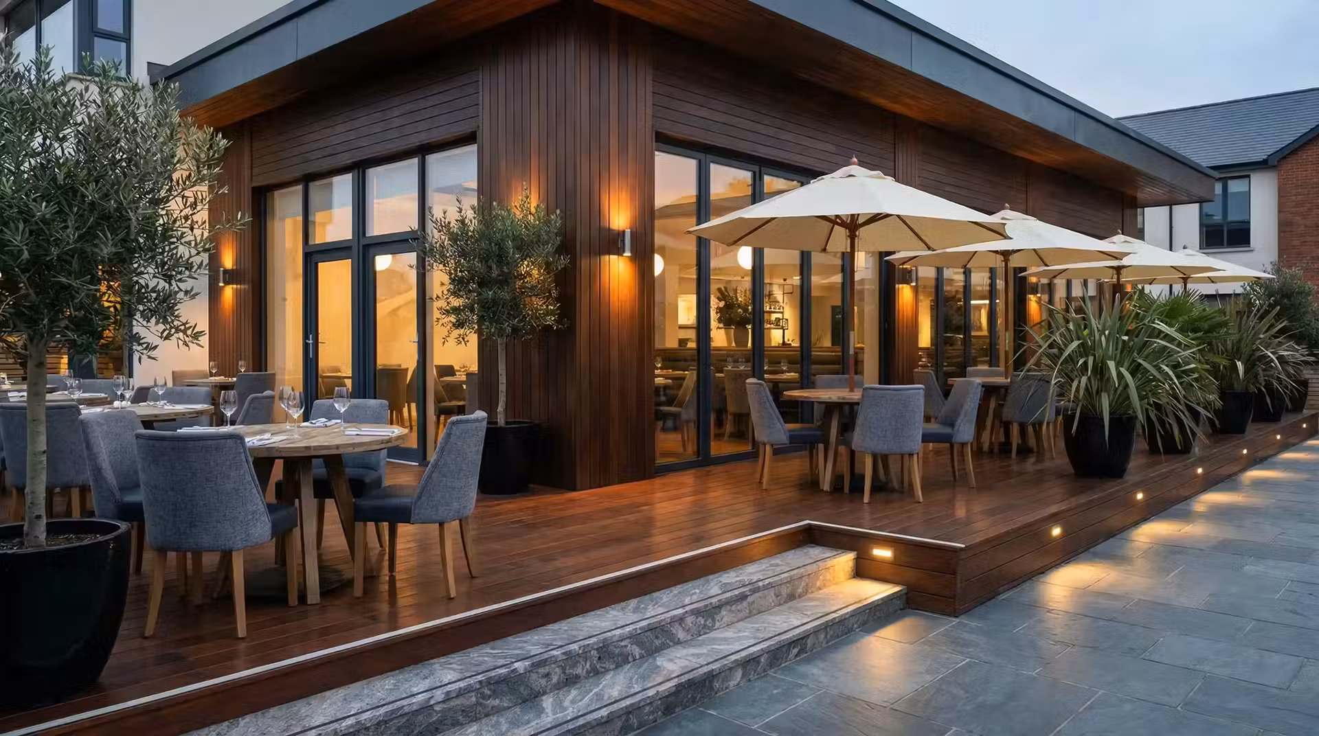 inquadratura ampia e suggestiva di un cortile ristorante elegante al tramonto con luci calde e tavoli apparecchiati